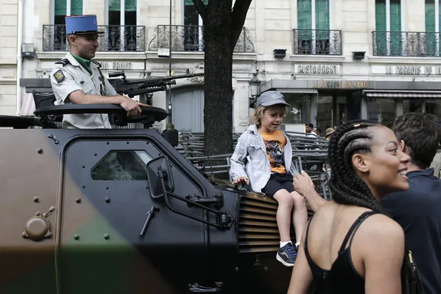 A child sits on a tank before Bastille Day parade Sunday, July 14, 2019 near the Champs Elysees avenue in Paris. (Photo by Rafael Yaghobzadeh/AP Photo)