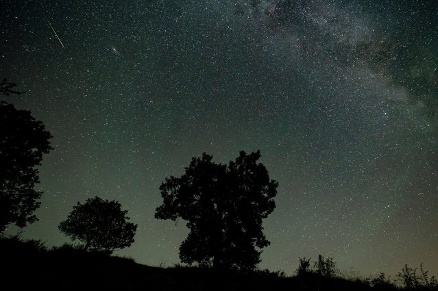 In this photo taken with long shutter speed, a shooting star is seen during the Perseids meteor shower above Holloko, Hungary, early Sunday, August 13, 2023. The Perseid meteor shower occurs every year in August when the Earth passes through debris and dust of the Swift-Tuttle comet. (Photo by Peter Komka/MTI via AP Photo)