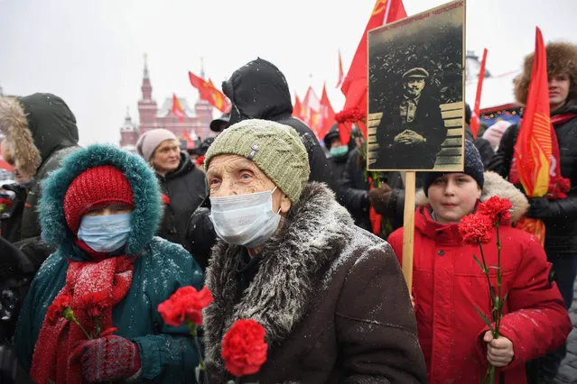 Russian Communist Party supporters hold flags and pictures as they take part in a memorial ceremony to mark the 98th anniversary of the death of Russian Communist revolutionary Vladimir Ulyanov, also known as Lenin, near his mausoleum at the Red Square in Moscow on January 21, 2022. (Photo by Natalia Kolesnikova/AFP Photo)