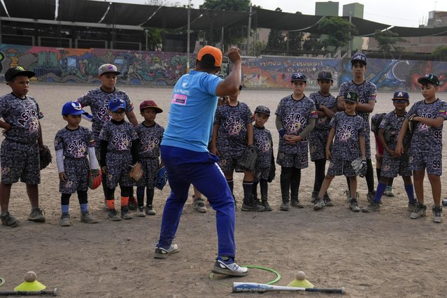 Baseball coach Franklin Lopez shows young Venezuelan migrants how to throw a ball during a baseball practice session in a public park in the Comas area, on the outskirts of Lima, Peru, May 2, 2024. (Photo by Martin Mejia/AP Photo)