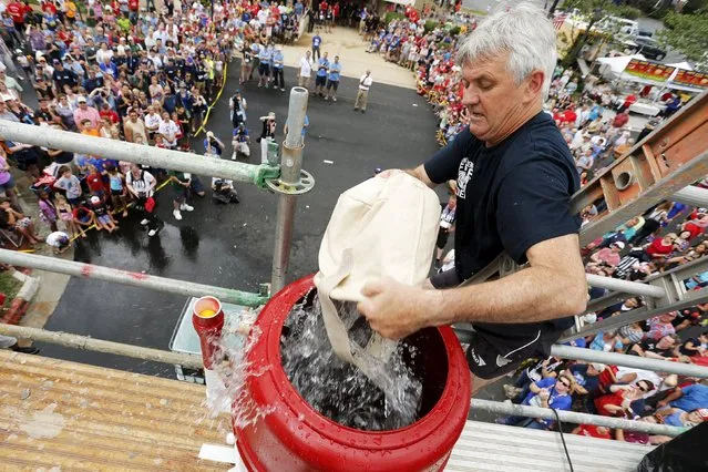 Ludovicus Poisson of a Belgian team from Antwerp empties buckets of water in the bucket brigade competition of the Firefighter Muster event at the World Fire and Police Games in Fairfax, Virginia July 4, 2015. (Photo by Jonathan Ernst/Reuters)