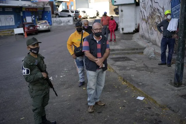 People line up at a site set up by the National Election Council (CNE) where people can sign a petition in favor of holding a referendum to remove President Nicolas Maduro from office in Caracas, Venezuela, Wednesday, January 26, 2022. The signatures of 20 percent of registered voter must be collected within 12 hours to request a presidential recall, a CNE rule that Maduro's opposition criticizes as impossible. (Photo by Matias Delacroix/AP Photo)