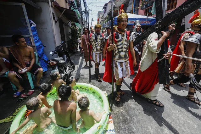 Children in a small pool watch Filipino Gerardo Galvez Jr. (R), portraying a suffering Jesus Christ in a local community play called “Senakulo” in Mandaluyong, east of Manila, Philippines, 13 April 2017. During Lent many Catholics in the Philippines subject themselves to several forms of self-inflicted pain like flagellation as a sign of faith and to seek forgiveness for their sins, despite calls from the Catholic Church to refrain from doing these physical forms of penance. (Photo by Rolex Dela Pena/EPA)