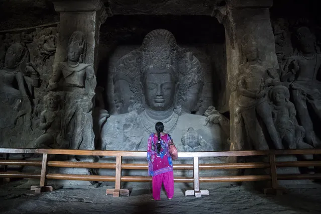 A woman stands in front of a large carving in the Elephanta Caves, a UNESCO World Heritage Centre and contain a collection of rock art linked to the cult of Shiva, on Elephanta Island in Navi Mumbai, India on Tuesday May 10, 2016. (Photo by Jabin Botsford/The Washington Post)
