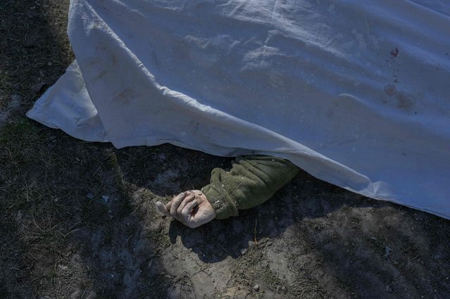 A picture taken on March 19, 2022 shows the body of a Ukrainian soldier covered with a sheet next to the military school hit by Russian rockets the day before, in Mykolaiv, southern Ukraine. Ukrainian media reported that Russian forces had carried out a large-scale air strike on Mykolaiv, killing at least 40 Ukrainian soldiers at their brigade headquarters. (Photo by Bulent Kilic/AFP Photo)
