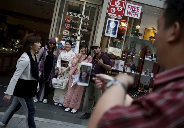 Foreign tourists pose with shop clerks for pictures outside a duty free store at Ginza shopping district in Tokyo, Japan, March 31, 2016. (Photo by Yuya Shino/Reuters)