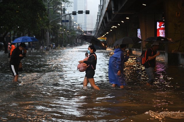 Pedestrians cross a flooded street in Manila on July 24, 2024 amid heavy rains brought by Typhoon Gaemi. Relentless rain drenched the northern Philippines on July 24, triggering flooding in Manila and landslides in mountainous regions as Typhoon Gaemi intensified the seasonal monsoon. (Photo by Ted Aljibe/AFP Photo)