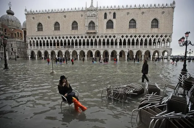 A woman sits in a chair in a flooded St. Mark's Square, in Venice, Wednesday, November 13, 2019. The high-water mark hit 187 centimeters (74 inches) late Tuesday, Nov. 12, 2019, meaning more than 85% of the city was flooded. The highest level ever recorded was 194 centimeters (76 inches) during infamous flooding in 1966. (Photo by Luca Bruno/AP Photo)