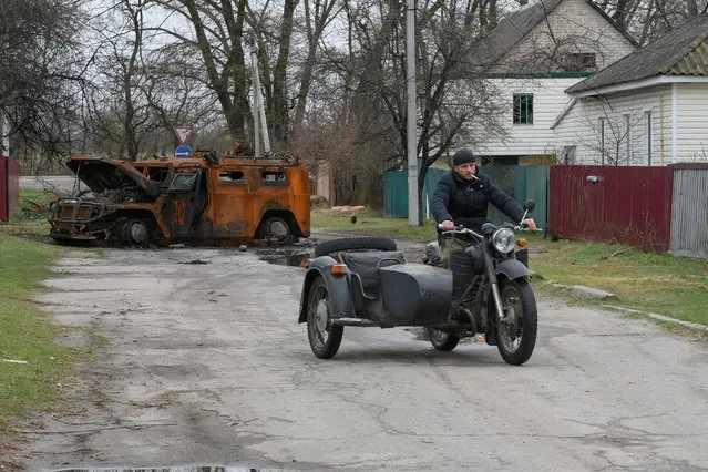 A local resident rides a motorcycle next to a Russian armoured vehicle destroyed during Russia's invasion, in the village of Yahidne, Ukraine April 20, 2022. (Photo by Vladyslav Musiienko/Reuters)