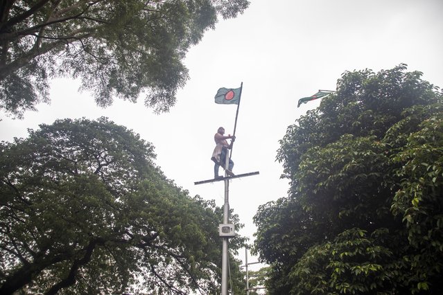 A protester holds the Bangladeshi national flag while standing on a street pole during a demonstration at the Central Shaheed Minar in Dhaka, Bangladesh, 03 August 2024. The Anti-Discrimination Student Movement organizers are demanding the resignation of the current government. They also announced plans to initiate a non-cooperation movement starting 04 August 2024. Authorities in Bangladesh have announced a gradual easing of the curfew imposed after mass protests last week, allowing offices to open and some activity, and partially restoring telecommunication services. As casualties mounted and law enforcement struggled to contain the unrest, the Bangladeshi government on 20 July 2024 imposed a nationwide curfew and deployed military forces after violence broke out in Dhaka and other regions following student-led protests demanding reforms to the government's job quota system. (Photo by Monirul Alam/EPA/EFE)