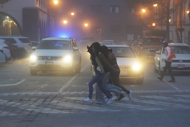 Women walk through the streets covered in ash from the Popocatépetl volcano in Atlixco, Mexico, Monday, May 22, 2023. The volcano's activity has increased over the past week. Evacuations have not been ordered, but authorities are preparing for that scenario and telling people to stay out of 7.5-mile (12-kilometer) radius around the peak. (Photo by Marco Ugarte/AP Photo)