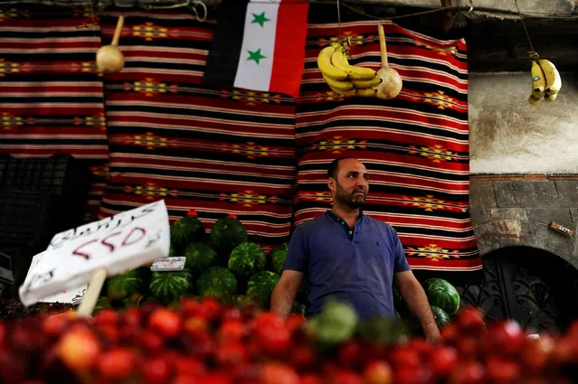 A vendor waits for customers in his stall ahead of the Muslim fasting month of Ramadan in the old Damascus, Syria, June 5, 2016. A Syrian national flag is seen in the background. (Photo by Omar Sanadiki/Reuters)