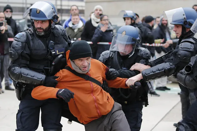 Riot police officers detain a striking train worker outside the the Gare de Lyon train station, Monday, December 23, 2019 in Paris. A wildcat protest comes on Day 19 of nationwide strike over the government's plans to raise the retirement age to 64. The union-led protest Monday led to a standoff with riot police that spilled onto the streets around the historic Gare de Lyon train station. (Photo by Francois Mori/AP Photo)