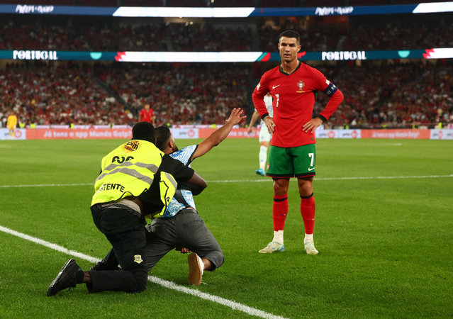 A pitch invader is detained as Portugal's Cristiano Ronaldo looks on during their Nations League match against Scotland in Lisbon, Portugal on September 8, 2024. (Photo by Pedro Nunes/Reuters)