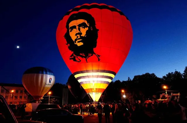 In this photo taken on Monday, June 13, 2016, a hot air balloon with the the image of Argentine revolutionary Che Guevara printed on it's side prepares to lift off during a ballooning festival in Velikiye Luki, Russia. (Photo by Maxim Marmur/AP Photo)