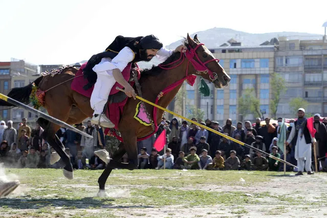 An Afghan man rushes to the target with his horse during spear racing in the sprawling Chaman-e-Huzori park in downtown Kabul, Afghanistan, Friday, May 6, 2022. (Photo by Ebrahim Noroozi/AP Photo)