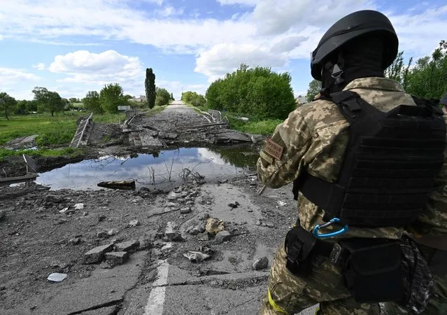 A Ukrainian serviceman stands next to a destroyed bridge near the village of Rus'ka Lozova, north of Kharkiv, on May 28, 2022, amid Russian invasion of Ukraine. (Photo by Genya Savilov/AFP Photo)