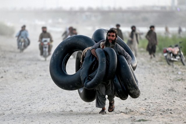 An Afghan man carries inflatable tubes along a riverside in Lashkar Gah, capital of Helmand province on August 26, 2024. (Photo by Wakil Kohsar/AFP Photo)