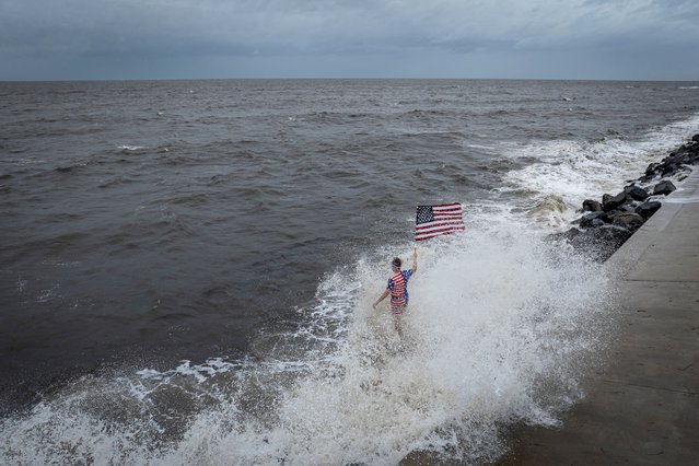 A person holding an American flag and being splashed by a crashing wave stands on the coastline as Hurricane Helene intensifies before its expected landfall on Florida’s Big Bend, in Alligator Point, Florida on September 26, 2024. (Photo by Marco Bello/Reuters)