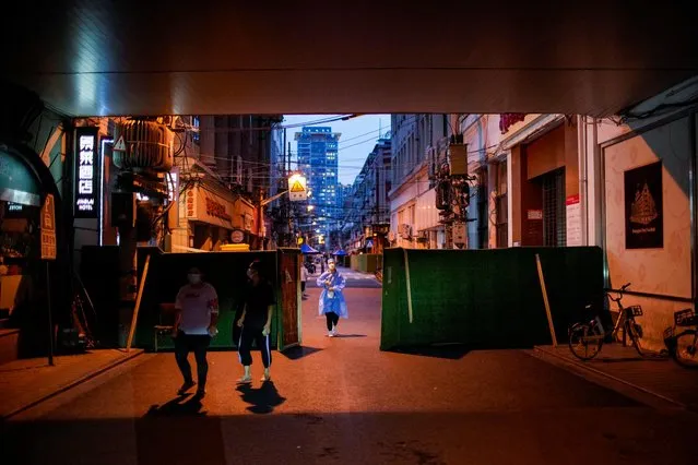 People walk out of a barrier at a residential area during lockdown, amid the coronavirus disease (COVID-19) outbreak, in Shanghai, China, May 30, 2022. (Photo by Aly Song/Reuters)