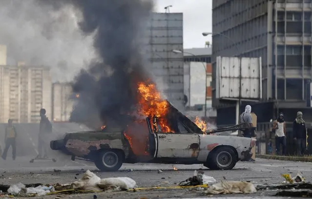 A car is engulfed in flames, set on fire by anti-government demonstrations during clashes with National Guards in Caracas, Venezuela, Thursday, July 20, 2017. (Photo by Ariana Cubillos/AP Photo)