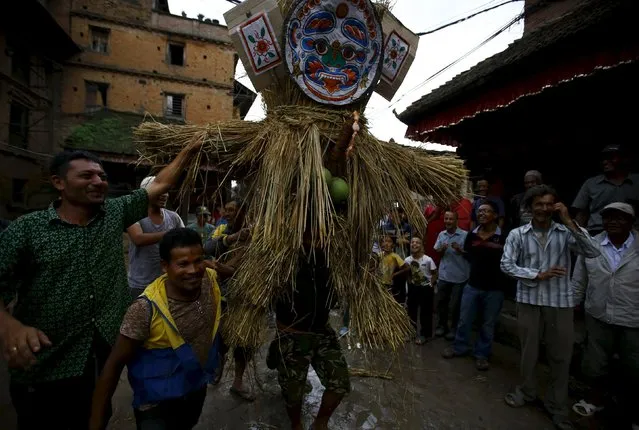 People carry an effigy of the demon Ghantakarna, before it is burnt to symbolize the destruction of evil, during the Ghantakarna festival at the ancient city of Bhaktapur, Nepal August 12, 2015. (Photo by Navesh Chitrakar/Reuters)