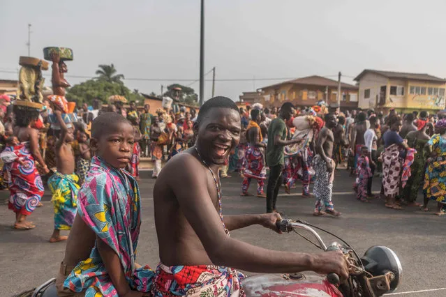 Voodoo devotees follow the parade on a motorcycle on the main boulevard of Porto-novo, in Benin on January 11, 2020. (Photo by Yanick Folly/AFP Photo)