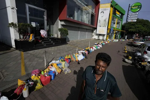 A man waits to buy kerosene oil standing by a line of empty canisters placed outside a fuel station amid shortage of cooking gas in Colombo, Sri Lanka, Thursday, June 23, 2022. Sri Lankans have endured months of shortages of food, fuel and other necessities due to the country’s dwindling foreign exchange reserves and mounting debt, worsened by the pandemic and other longer term troubles. (Photo by Eranga Jayawardena/AP Photo)