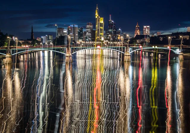 Picture taken with long time exposure shows night lights of the banking district in Frankfurt am Main, western Germany, reflecting in the water of the river Main on July 30, 2017. (Photo by Frank Rumpenhorst/AFP Photo/DPA)
