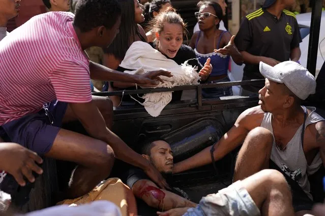 Residents transport a wounded man in the back of a truck after a police operation that resulted in multiple deaths, in the Complexo do Alemao favela in Rio de Janeiro, Brazil, Thursday, July 21, 2022. (Photo by Silvia Izquierdo/AP Photo)