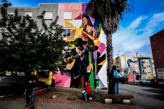 Visitors take pictures of a murals by Russian artist Zmock (L) and Portuguese artist Bordalo II (R) during a guided visit to Quinta do Mocho neighbourhood in Sacavem, outskirts of Lisbon, on November 11, 2019. (Photo by Patricia De Melo Moreira/AFP Photo)