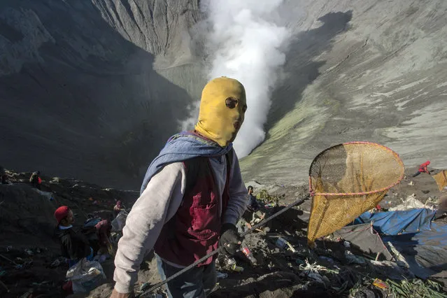 Non-Hindus carry nets as they wait on the edge of the crater to catch offerings cast down by Hindus during the Kasodo ceremony at Mount Bromo, Probolinggo, Indonesia, August 12, 2014. The Kasodo ceremony is a way of Tengger Hindus to express their gratitude to God for good harvest and fortune. The offerings range from vegetables to chickens, from fruits to goats, from money to other valuables. (Photo by Fully Handoko/EPA)