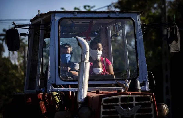 A family rides their tractor through the countryside wearing masks as a precaution against the spread of the new coronavirus in Havana, Cuba, Wednesday, April 8, 2020. Cuban authorities are requiring the use of masks for anyone outside their homes. (Photo by Ramon Espinosa/AP Photo)