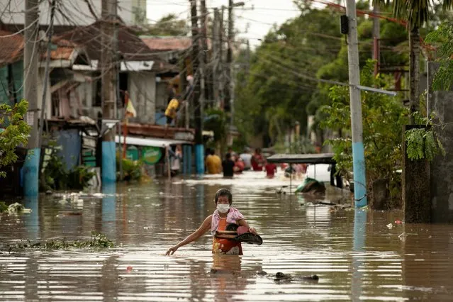 Residents wade through waist-deep flood waters after Super Typhoon Noru, in San Miguel, Bulacan province, Philippines on September 26, 2022. (Photo by Eloisa Lopez/Reuters)