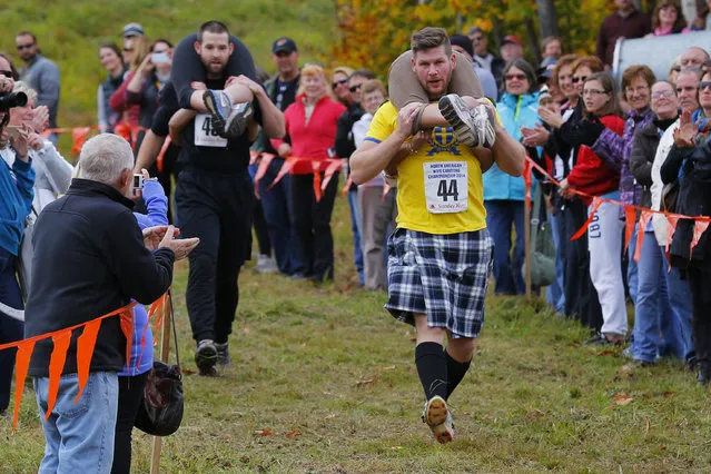 Christian Carlsson (44) carries Tuyet Nguyen ahead of Kevin Chamberlain (rear), carrying Chantal Colpitts, in the North American Wife Carrying Championship at Sunday River ski resort in Newry, Maine October 11, 2014. REUTERS/Brian Snyder