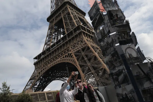 Visitors take a selfie at the main entrance during the opening up of the top floor of the Eiffel Tower, Wednesday, July 15, 2020 in Paris. The top floor of Paris' Eiffel Tower reopened today as the 19th century iron monument re-opened its first two floors on June 26 following its longest closure since World War II. (Photo by Francois Mori/AP Photo)