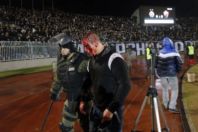 A policeman arrests a supporter after clashes between Red star Belgrade' s and Partizan Belgrade' s hooligans during the Serbian Superleague derby football match between Partizan Belgrade and Crvena Zvezda (Red Star), on December 13, 2017 in Belgrade. (Photo by Pedja Milosavljevic/AFP Photo)