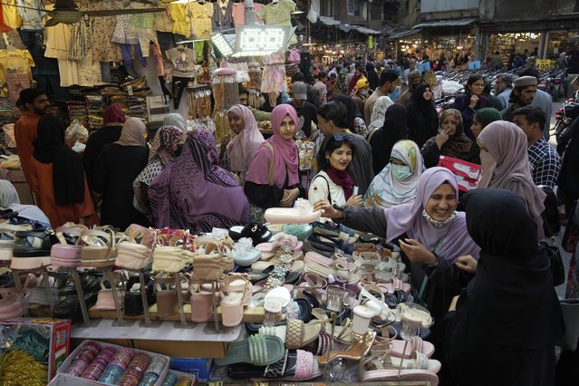 Women look at footwear as they visit a market to shop for the upcoming Eid al-Fitr celebrations, which marks the end of the Islamic holy month of Ramadan, in Lahore, Pakistan, Monday, March 24, 2025. (Photo by K.M. Chaudary/AP Photo)