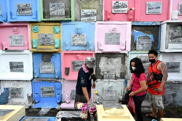 A man places flowers on a grave to mark All Saints’ Day at Manila North Cemetery in Manila on November 1, 2022. (Photo by Jam Sta Rosa/AFP Photo)