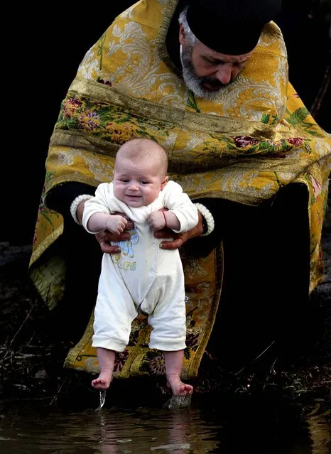 An Orthodox priest baptizes a baby in the icy waters of the Tundzha River during celebrations of the Feast of the Epiphany in Kalofer, Bulgaria, January 6, 2013. (Photo by Valentina Petrova/Associated Press)