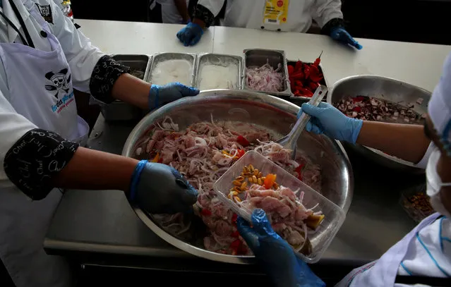 Cooks prepare traditional dish “Ceviche” during Mistura gastronomic fair, which promotes Peruvian cuisine by showcasing food and products from all over the country, in Lima, Peru, September 8, 2016. Ceviche is a seafood dish popular in the coastal regions of Mexico, Ecuador, Colombia, Chile and Perú and other parts of Latin America. The dish is typically made from fresh raw fish cured in citrus juices, such as lemon or lime, and spiced with ají or chili peppers. Additional seasonings, such as chopped onions, salt, and cilantro, may also be added. Ceviche is usually accompanied by side dishes that complement its flavors, such as sweet potato, lettuce, corn, avocado or plantain. (Photo by Mariana Bazo/Reuters)