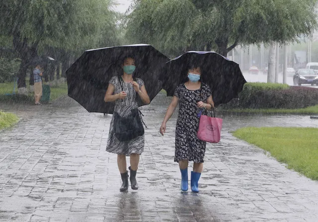Women walk with umbrellas during torrential rains, Wednesday, August 5, 2020, in Pyongyang. North Korea says torrential rains have lashed the country, prompting outside worries about possible big damages in the impoverished country. (Photo by Cha Song Ho/AP Photo)