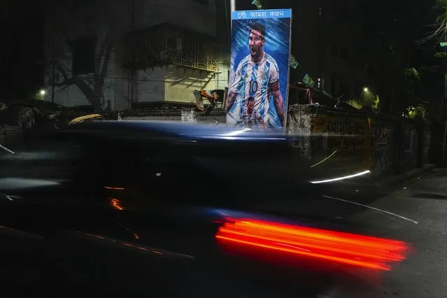 A car passes a poster of Argentina's Leonel Messi, erected by the Indian fans of Argentina during the World Cup semi final soccer match between Argentina and Croatia in Qatar, Wednesday, December 14, 2022. Argentina defeated Croatia 3-0. (Photo by Bikas Das/AP Photo)