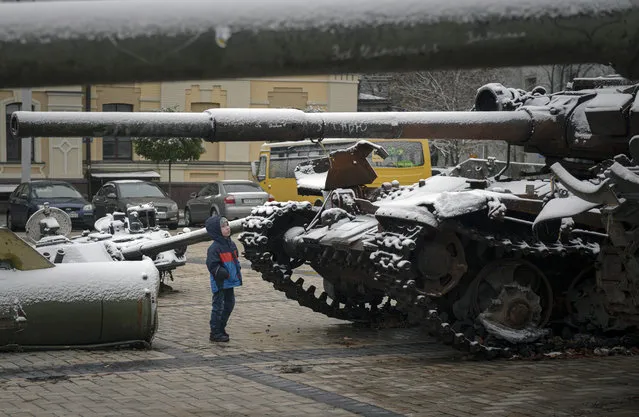 A child looks at a display of destroyed Russian tanks and armoured vehicles after snowfall in downtown Kyiv, Ukraine, Thursday, November 17, 2022. (Photo by Andrew Kravchenko/AP Photo)