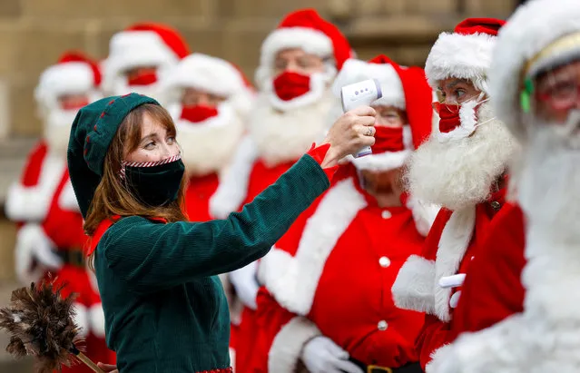 A woman dressed as an elf poses for a photo with attendees of the Ministry of Fun Santa School outside Southwark Cathedral, in London, Britain on August 24, 2020. (Photo by John Sibley/Reuters)