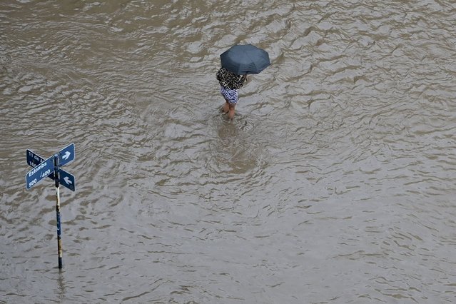 A person wades through a flooded street after a storm in Bahia Blanca, Argentina, Friday, March 7, 2025. (Photo by Juan Sebastian Lobos/AP Photo)