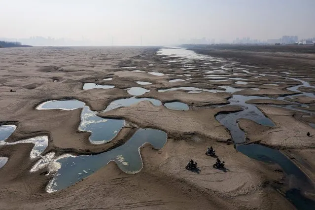 This photo taken on December 24, 2022 shows people riding scooters on a section of a parched river bed along the Yangtze River in Wuhan in China's central Hubei province. (Photo by AFP Photo/China Stringer Network)