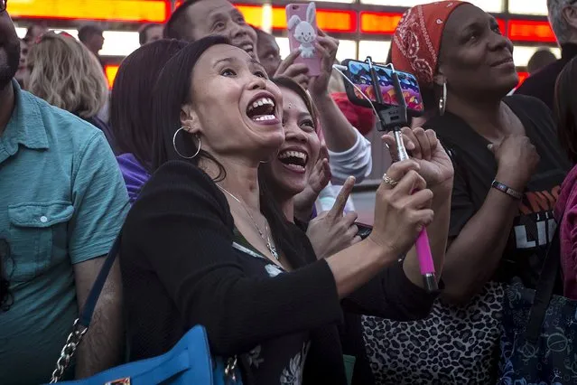 Woman laugh as their image is projected on a billboard owned by Revlon that takes their pictures and displays them in Times Square in the Manhattan borough of New York October 13, 2015. Cosmetics company Revlon switched on its "Kiss Cam" in New York's Times Square on Tuesday, four days after the interactive billboard went dark over complaints that it was attracting gropers. (Photo by Carlo Allegri/Reuters)