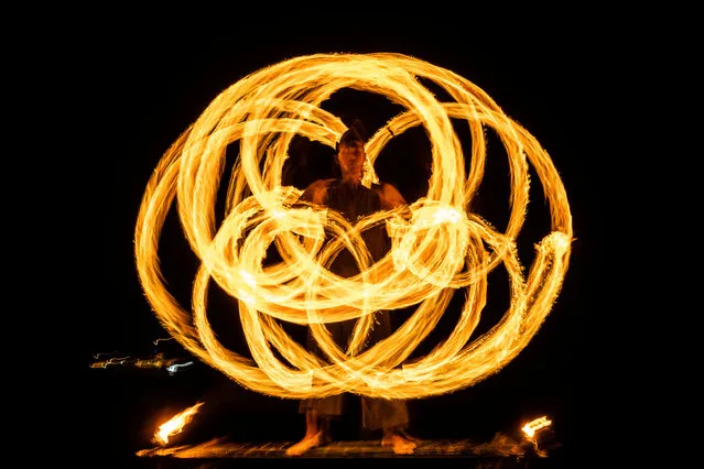 A performer takes part in a fire show at the beach in Phuket, Thailand on December 28, 2022. (Photo by Jorge Silva/Reuters)