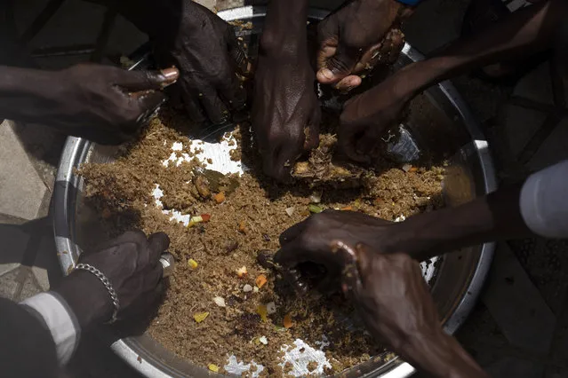Pilgrims from the Mouride Brotherhood share a big dish of traditional Senegalese food, distributed by volunteers, outside the Grand Mosque of Touba, as part of the celebrations of the Grand Magal of Touba, in Senegal, Tuesday, October 6, 2020. (Photo by Leo Correa/AP Photo)